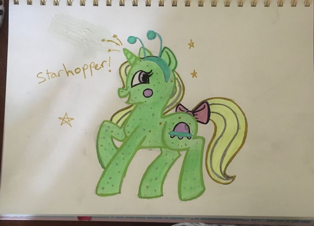 Traditional piece of the pony “Starhopper” in a g4 style. She’s a green glittery unicorn, with a blonde mane and tail with silver highlights. Her cutie mark is a purple UFO and she’s wearing a green alien bopper headband.