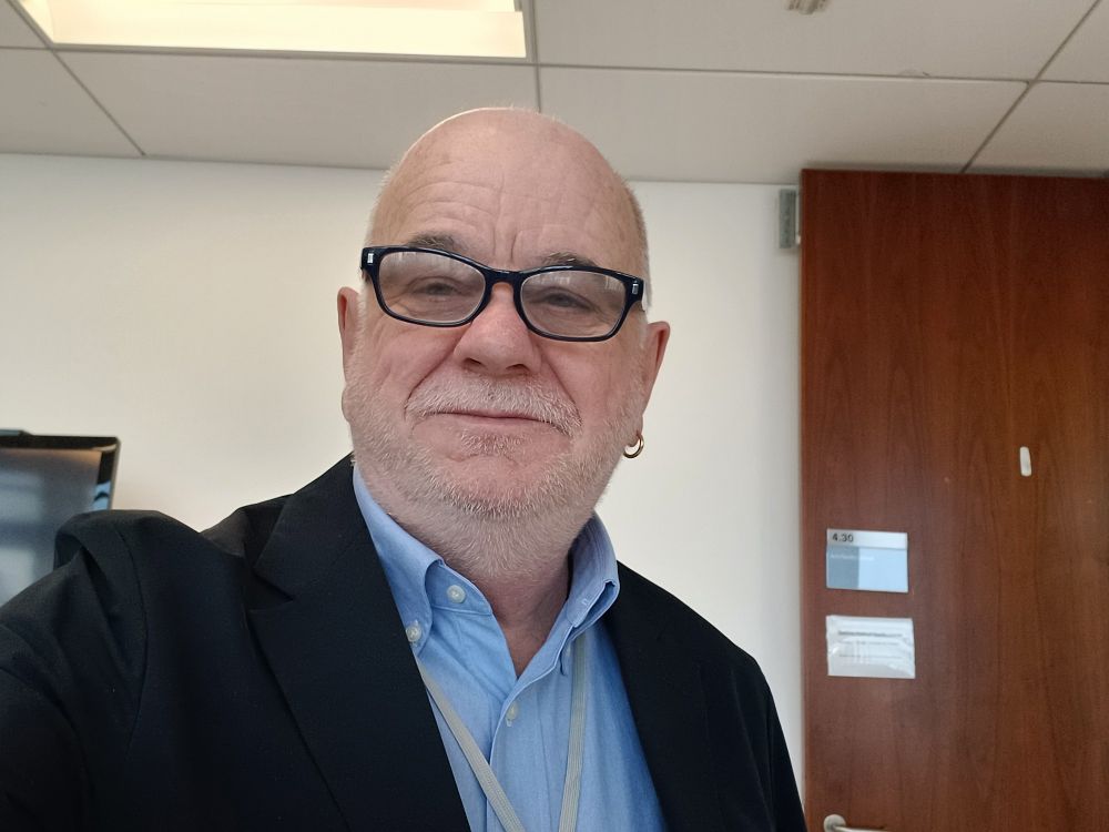A photo of Simon Mahony in conference uniform. 