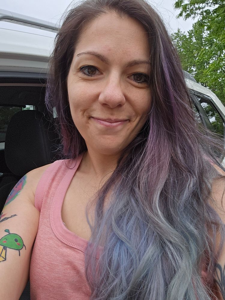 Elana with a small smile standing in front of an open car door