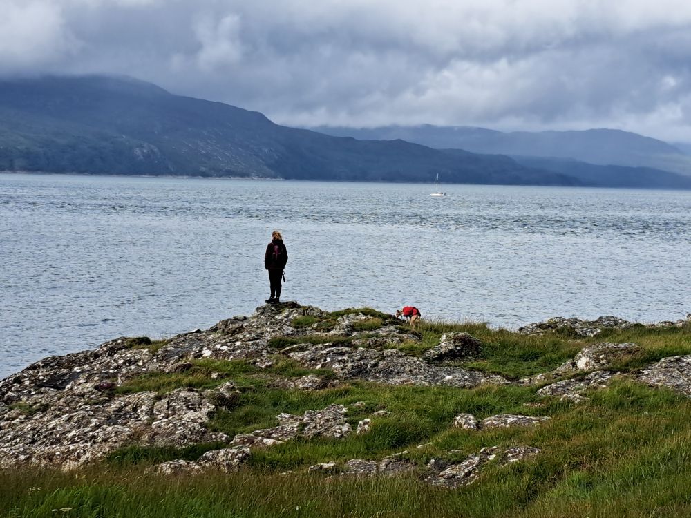 My wife and dog standing on the shore looking out to sea