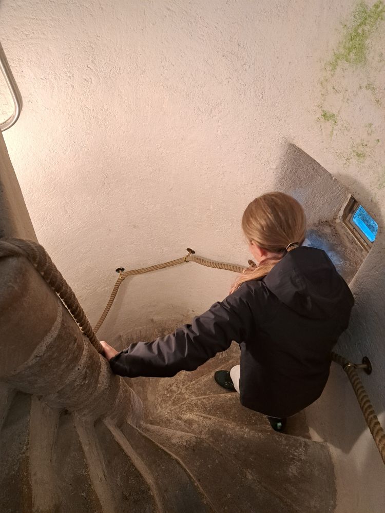 Eldest daughter walking down a narrow stone spiral staircase 