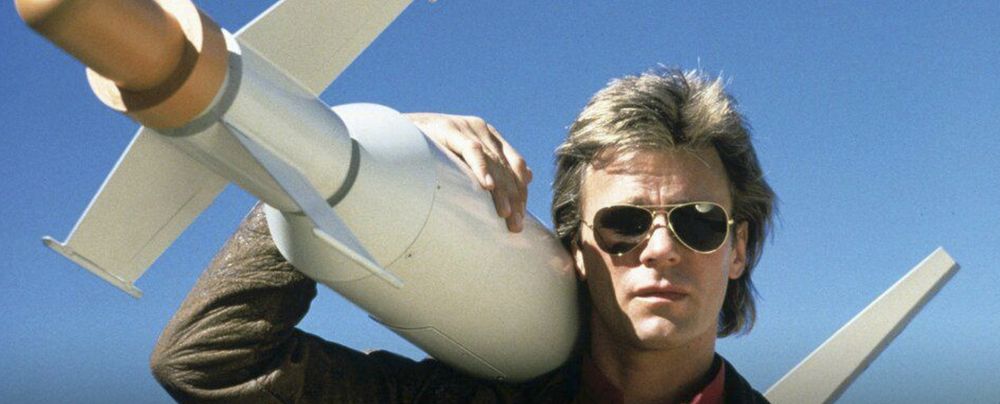 A promotional image of MacGyver, looking cool and carrying a missile, for the original '80s TV series.