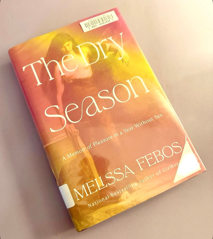 A book titled "The Dry Season: A Memoir of Pleasure in a Year Without Sex" by Melissa Febos on a lavender desk mat.