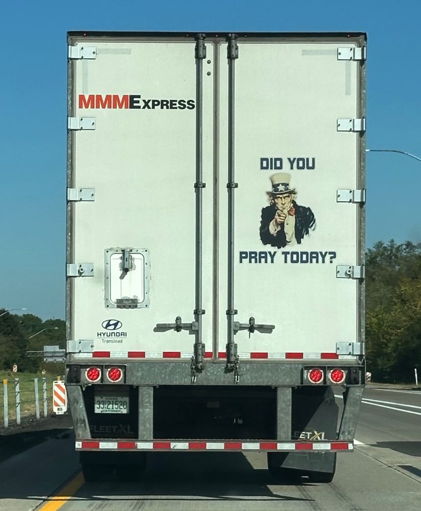 The back of a white MMMExpress semi on a public roadway. On the back door of the truck is a large image of Uncle Sam pointing directly at the viewer with the text "DID YOU PRAY TODAY?" around the image. 