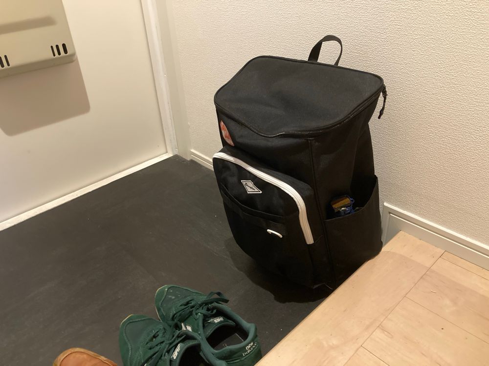 A black emergency bag sits in a genkan