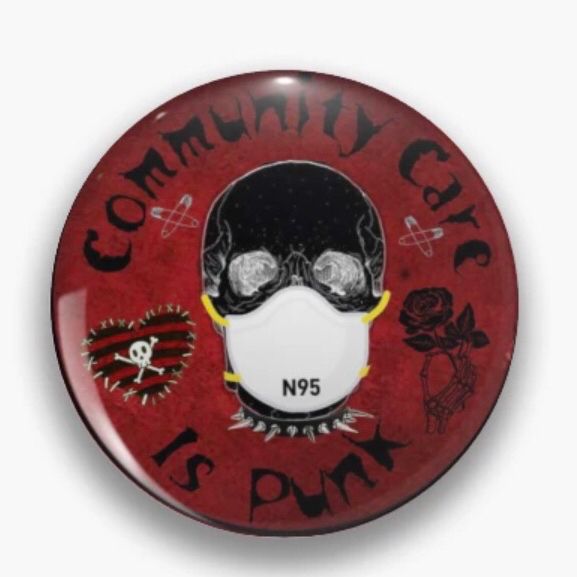 A dark red button that shows a grey skull wearing a white N95 mask. Around the edge, design items include a black rose, a red and black heart with a skull and crossbones in the center, and safety pins. Blocky black text reads: Community Care Is Punk