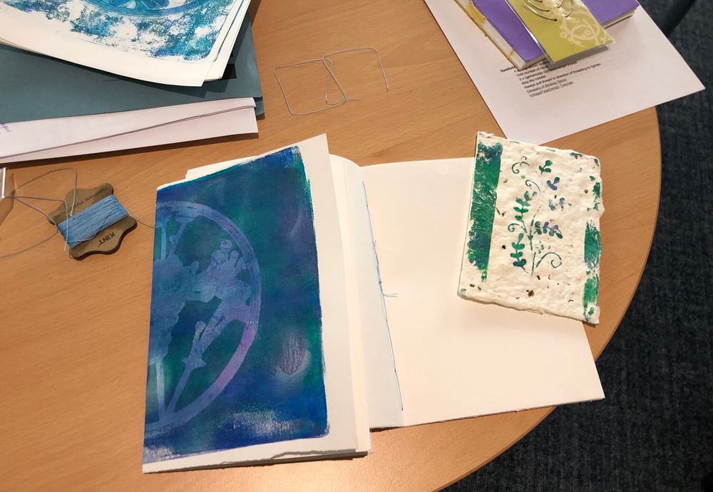 Handmade notebooks of a single signature with gelli printed botanical covers in blues and purples 