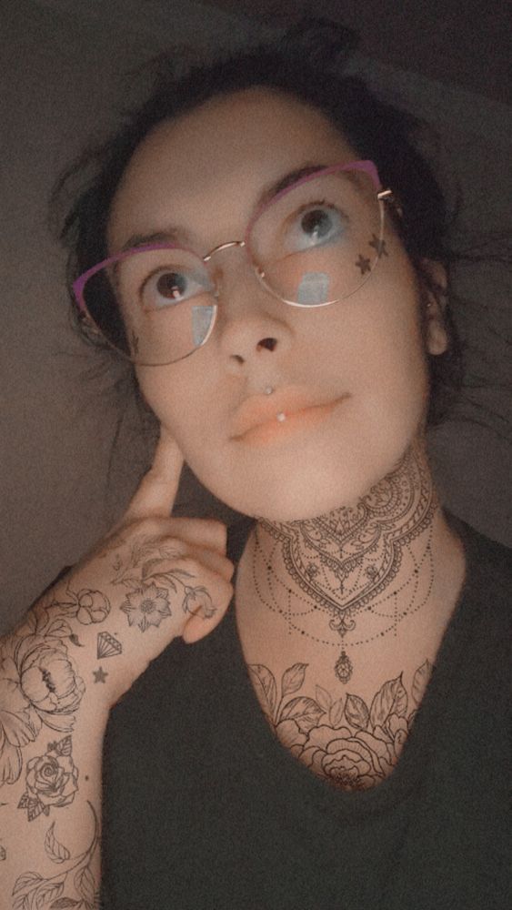 Snapchat selfie of Gabby Gray with "body tattoo" filter. Tattoo filter places tattoos on Gabby's neck, chest, arm, hand, and small star tattoos below each eye on her face.