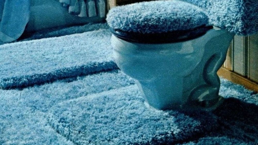 a bathroom covered in blue carpet. it is the worst.
