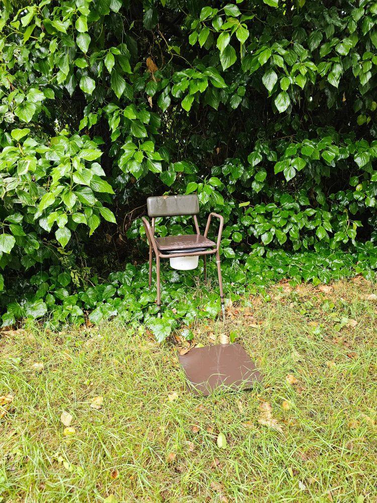 A commode chair thing inexplicably outdoors
