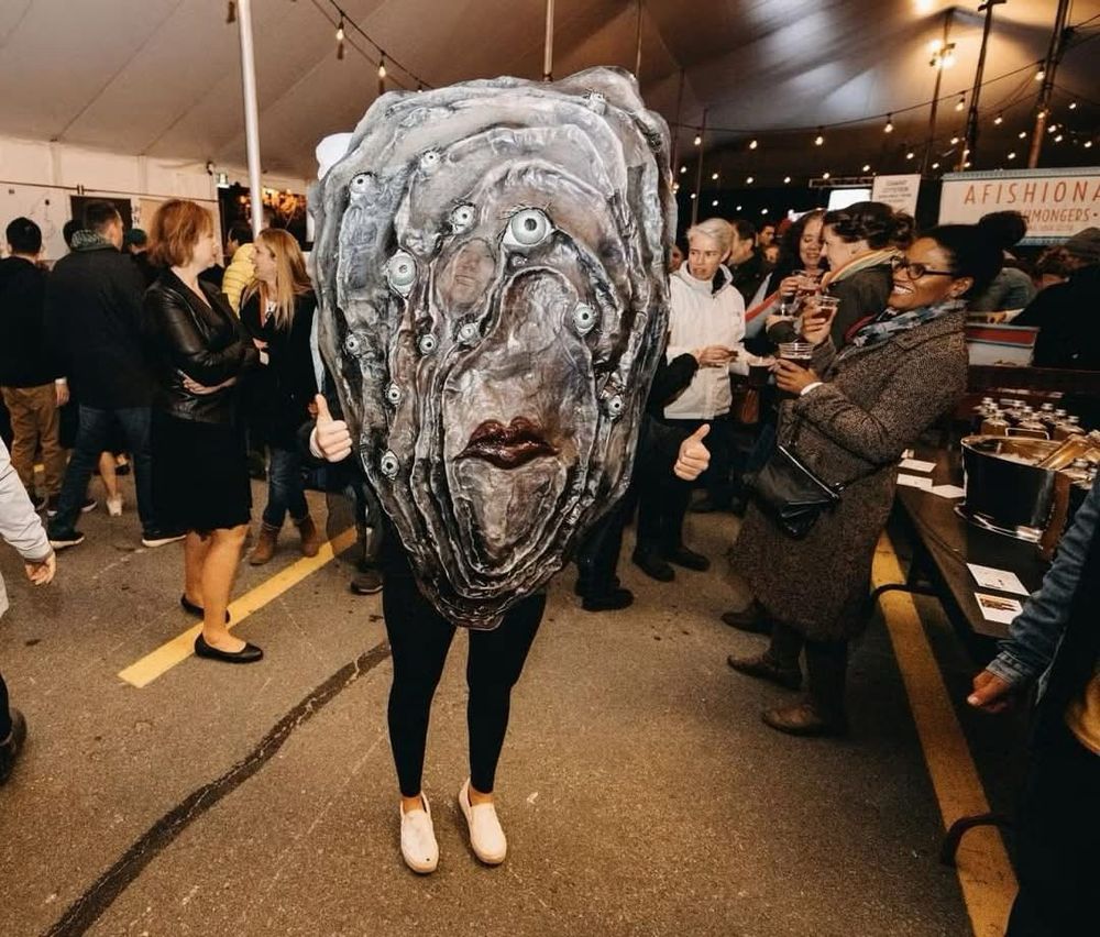 A person dressed up as an oyster giving the two thumbs up 