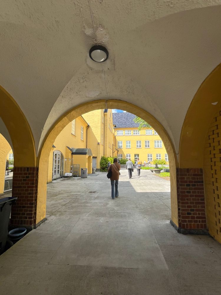 A person walking through a sunny archway in Sydneshaugen school. 
