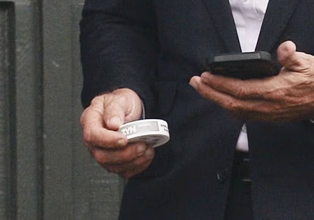A closeup of Robert F Kennedy Jr’s hand clutching a packet of Zyn nicotine replacement