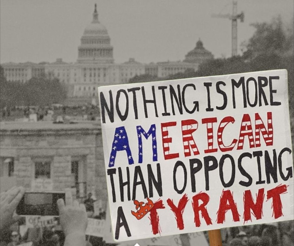 Black and white photo of a protest in front of the Capitol Building in DC with a protest sign colorized in red, white, and blue reading: Nothing is more American than opposing a tyrant. 