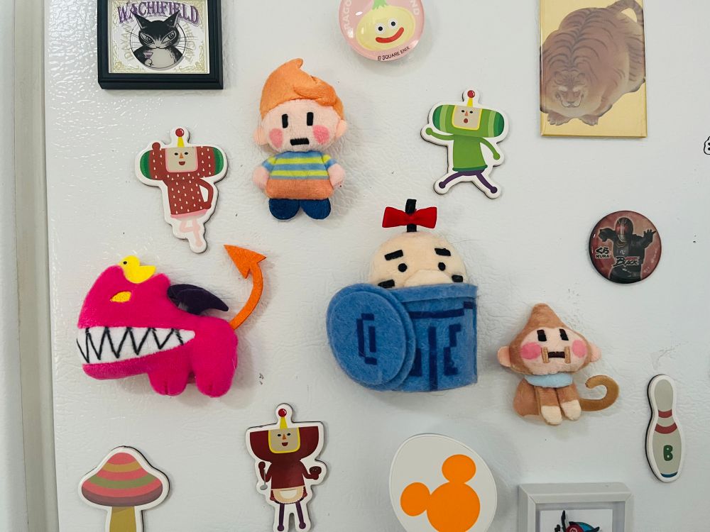 various magents on a fridge including plush magnets of Claus, Chimera, Salsa, and Mr Saturn from the Mother series