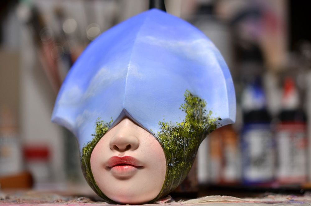 Hooded sculpture with a sky painted across the hood. 