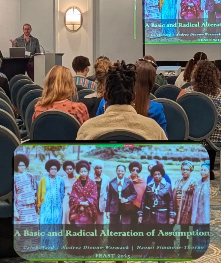 Me standing in front of an audience at the podium, with a slide in the foreground showing a photo of a 1973 gathering of Black women writers with the header “A Basic and Radical Alteration of Assumptions”