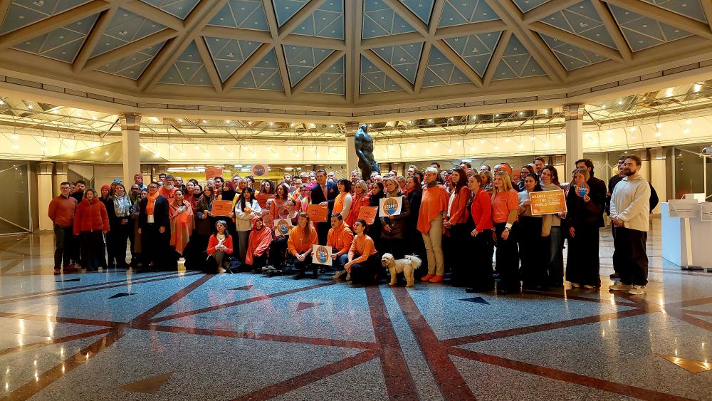 Gruppenbild mit orange gekleideten Mitarbeitenden des BMIMI im Foyer des Ministerium anlässlich der Orange the World Aktionstage