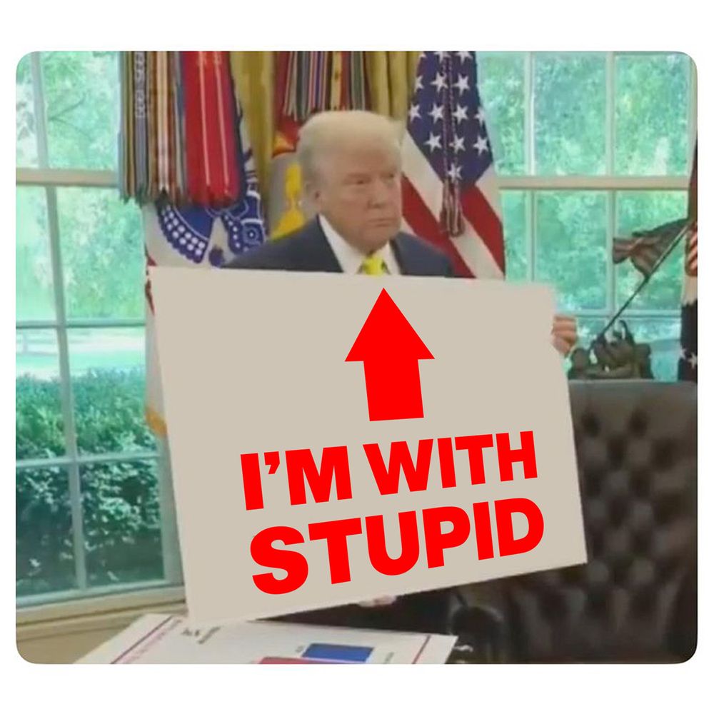 Trump holding up a sign with an arrow that's pointing to him. It says: I'm with stupid.
