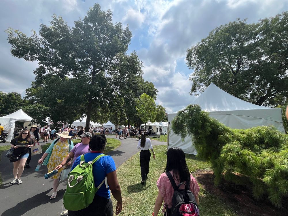 A view of the tents outside in the park at Columbus Book Fair, people walking among the grass and tents