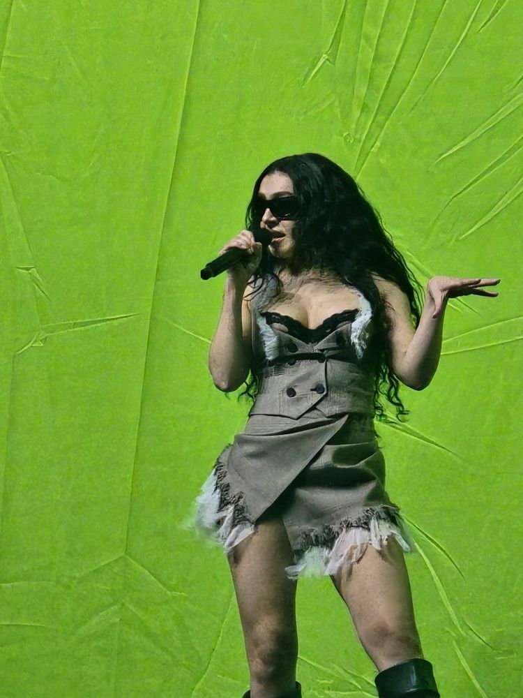 Charli xcx performing 360 in front of large brat banner 