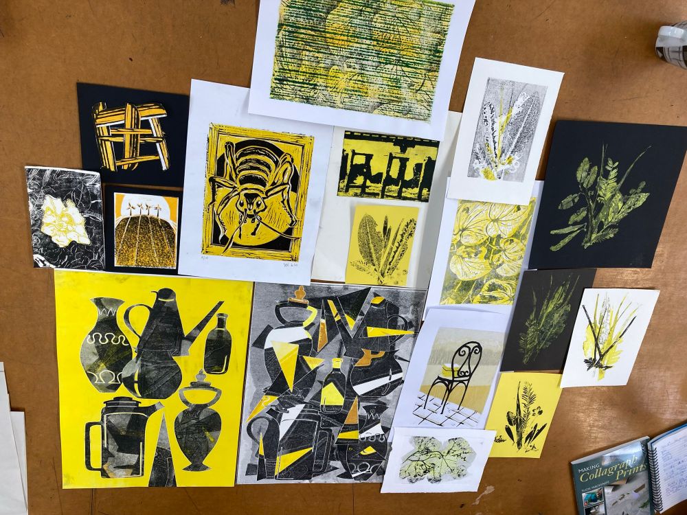 A selection of 16 prints by different artists laid on a table. All feature the colour yellow. Images include abstracts, a chair, pots, leaves, an insect, and a flower.