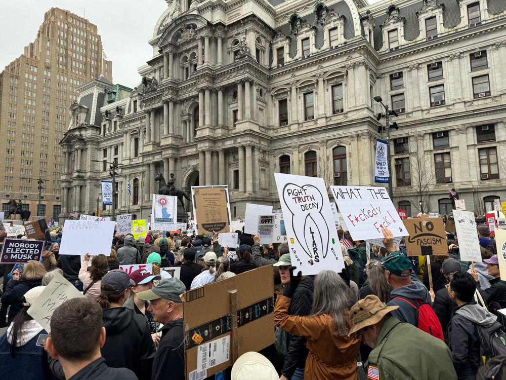 Protestors holding signs in front of Philadelphia City Hall 