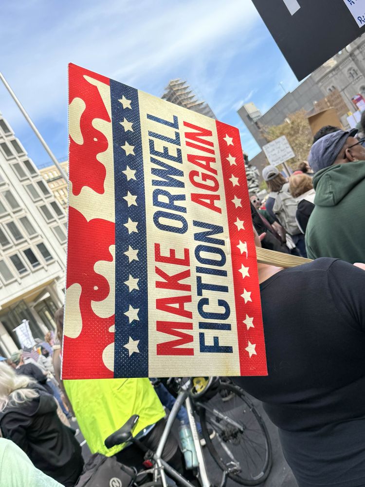 A sign that reads “make Orwell fiction again”