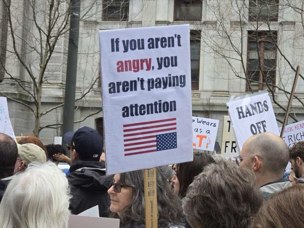 A protest sign reading Aug You Aren’t Angry , You Aren’t Paying Attention