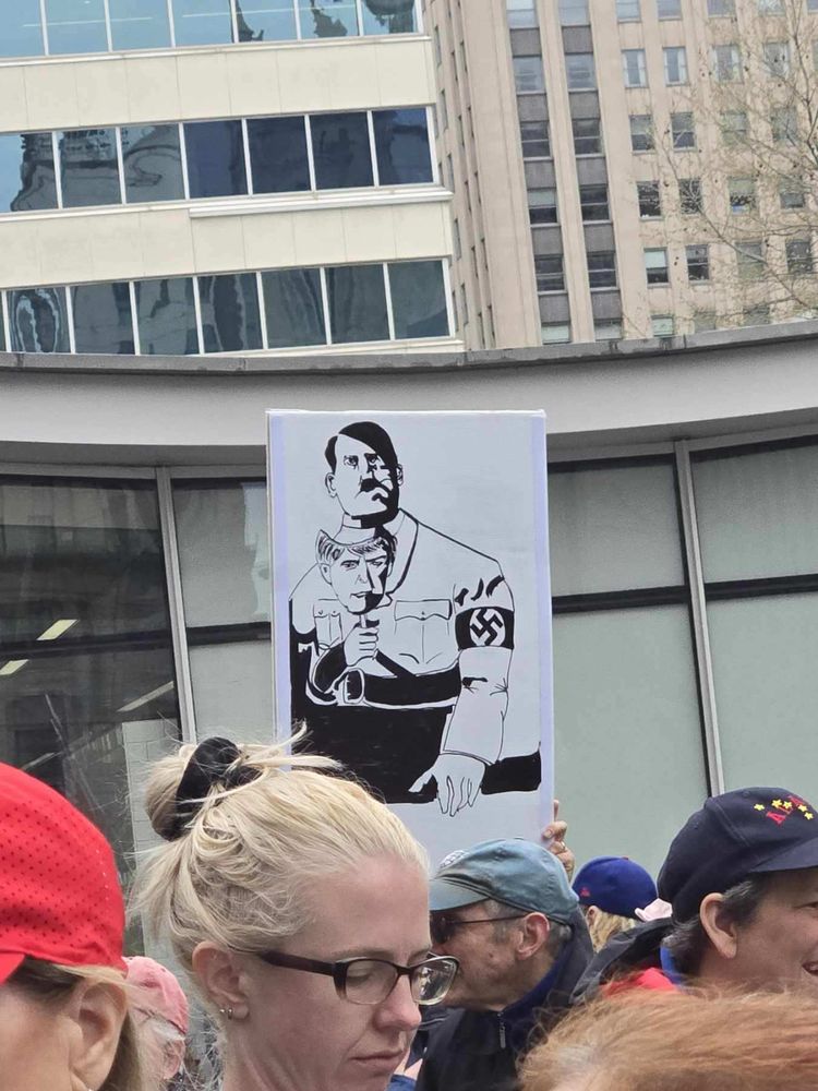 A drawing of a man letting his man down to reveal his real face. The mask is Trump. The real face is hitler’s. 
