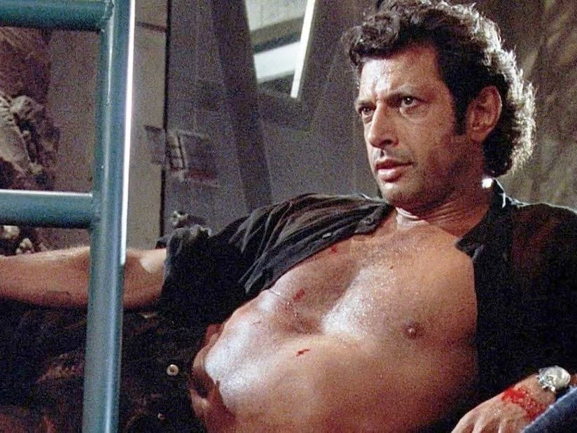 Jeff Goldblum, regard intense, torse nu, huilé.
