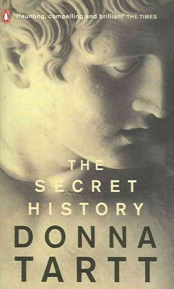 Image of the book cover of The Secret History by Donna Tartt. Cover image consists of a close up of the face of a Greek statue.