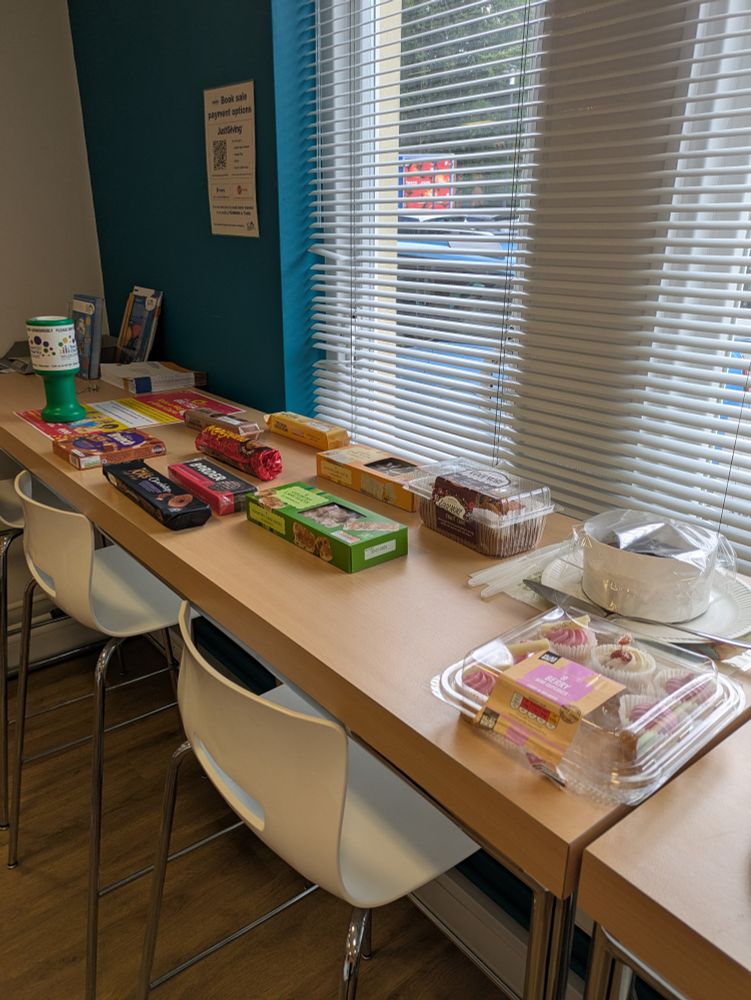 Biscuits and cakes spread out on a table next to a window.