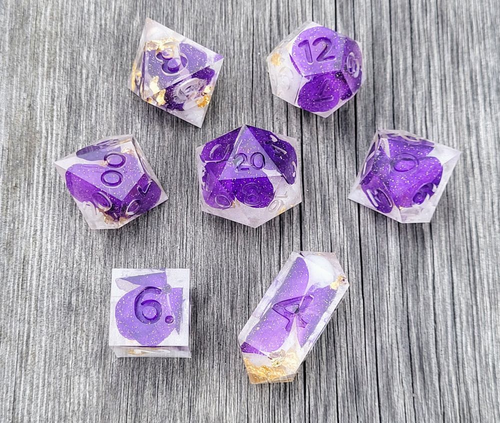 7 piece handmade dice set with dehydrated purple pansies, white ink & gold leaf inside; dice set is "raw" (unpolished & uninked) in photo