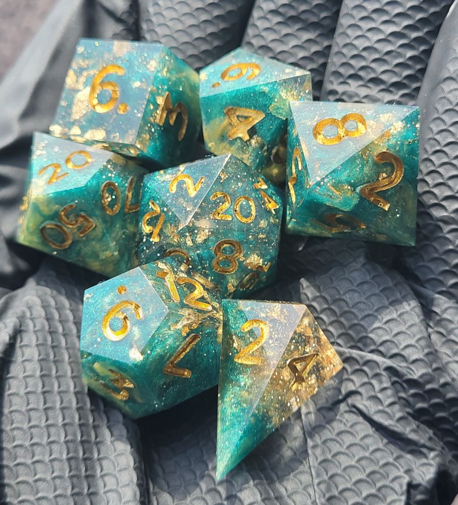 7 piece handmade polyhedral dice set done with green mica powders & gold leaf. Numbers are inked in a metallic gold.
