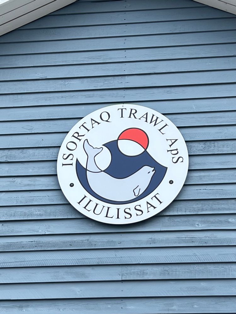 Logo for a fishing outfit showing a beluga intersecting with a wave and the Greenlandic flag