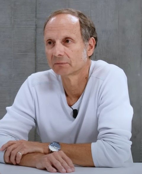 Frederic Lordon chez Blast, les bras posé sur la table, un air las, il porte un polo blanc