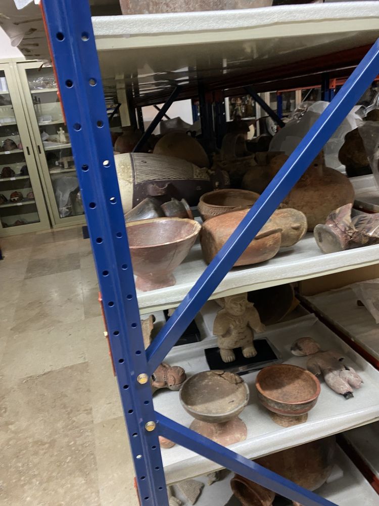 Museum storage lined with pots, masks, and figurines