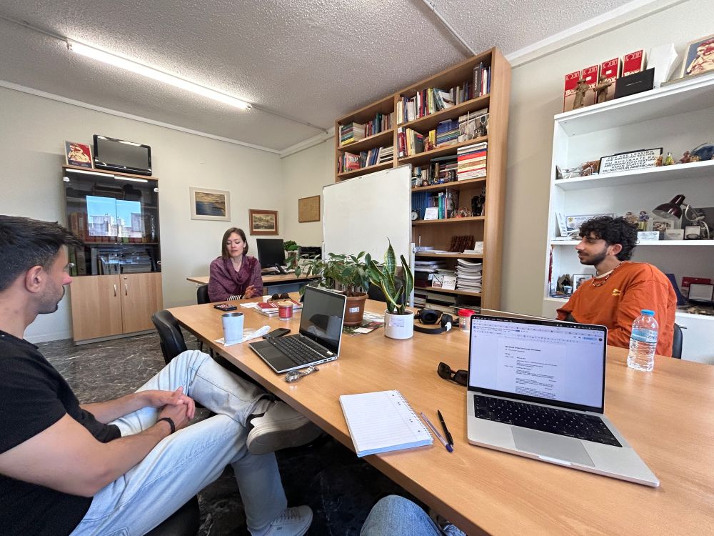 Three people sit around a table and discuss