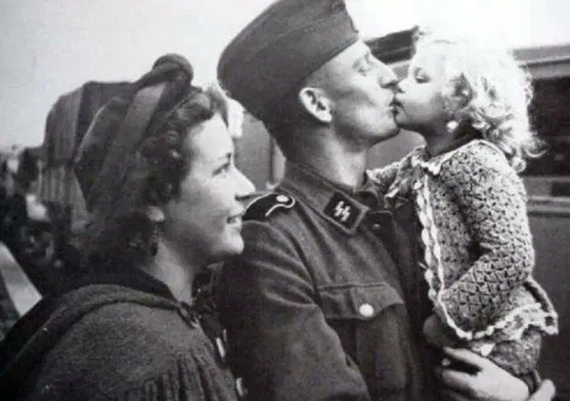 부인으로 추정되는 여성 곁에서 자녀로 추정되는 아이를 안고 입을 맞추는 나치 SS 대원