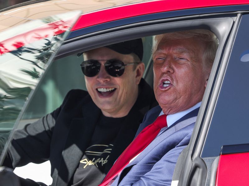 Trump e Musk dentro de um Teslas. Trump está fazendo bico e Musk sorrindo