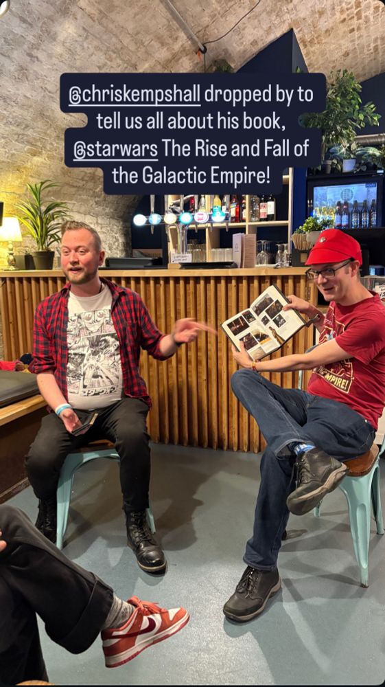A photo of Chris from DK and Chris Kempshall (in a red t-shirt and hat) holding up a copy of ‘Star Wars: The Rise and Fall of the Galactic Empire’ during a discussion of the book. 