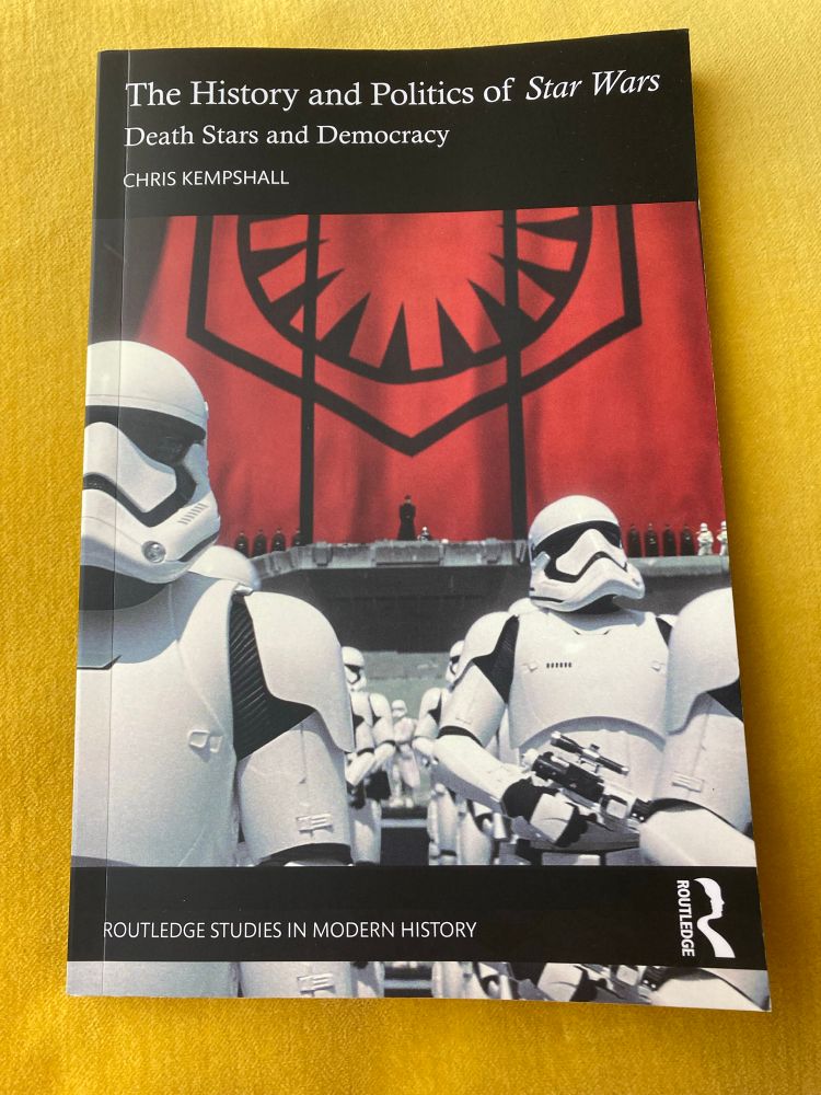 A copy of the book ‘The History and Politics of Star Wars’ on a yellow cushion. 