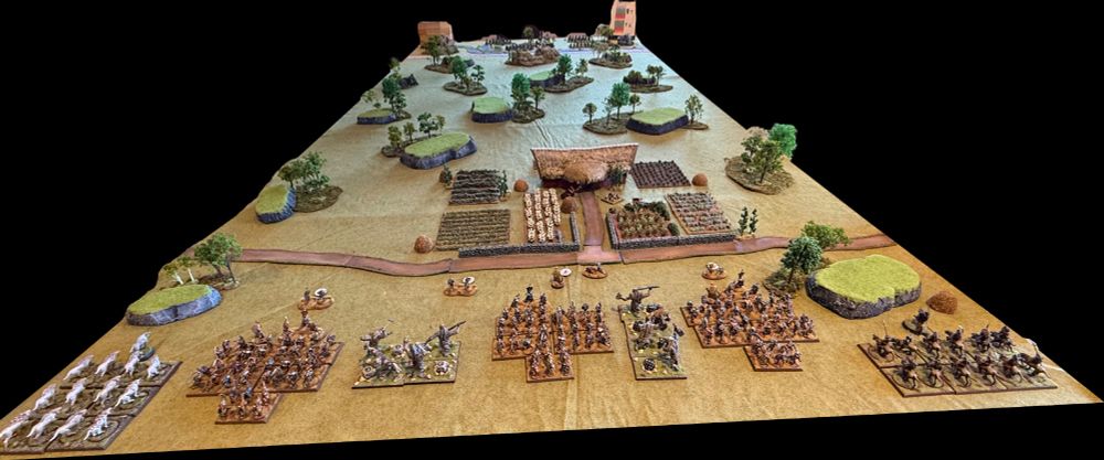 Picture of a gaming table with terrain and fantasy army pieces.