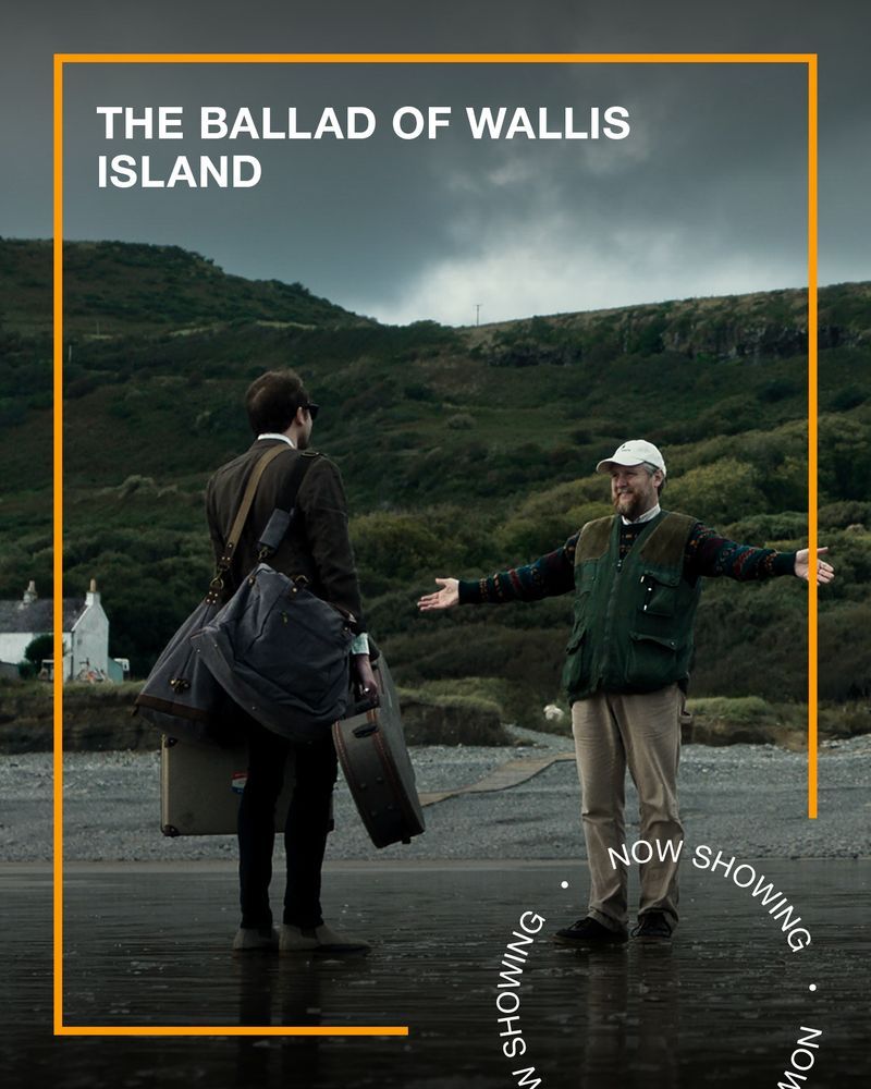 A man stands on the beach with his arms outstretched in welcome to another man who is holding a guitar case. Text - The Ballad of Wallis Island, Now Showing.
