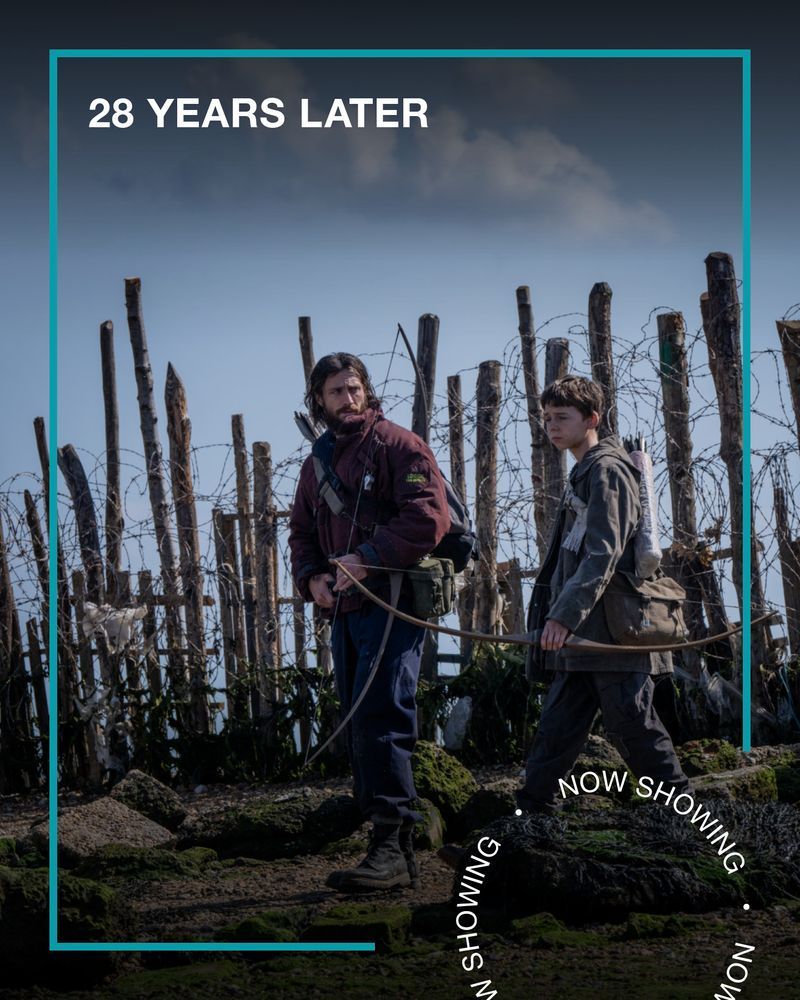 A man and a young boy walk by a jagged fence made of barbed wire, holding crossbows. Text - 28 Years Later, Now Showing.