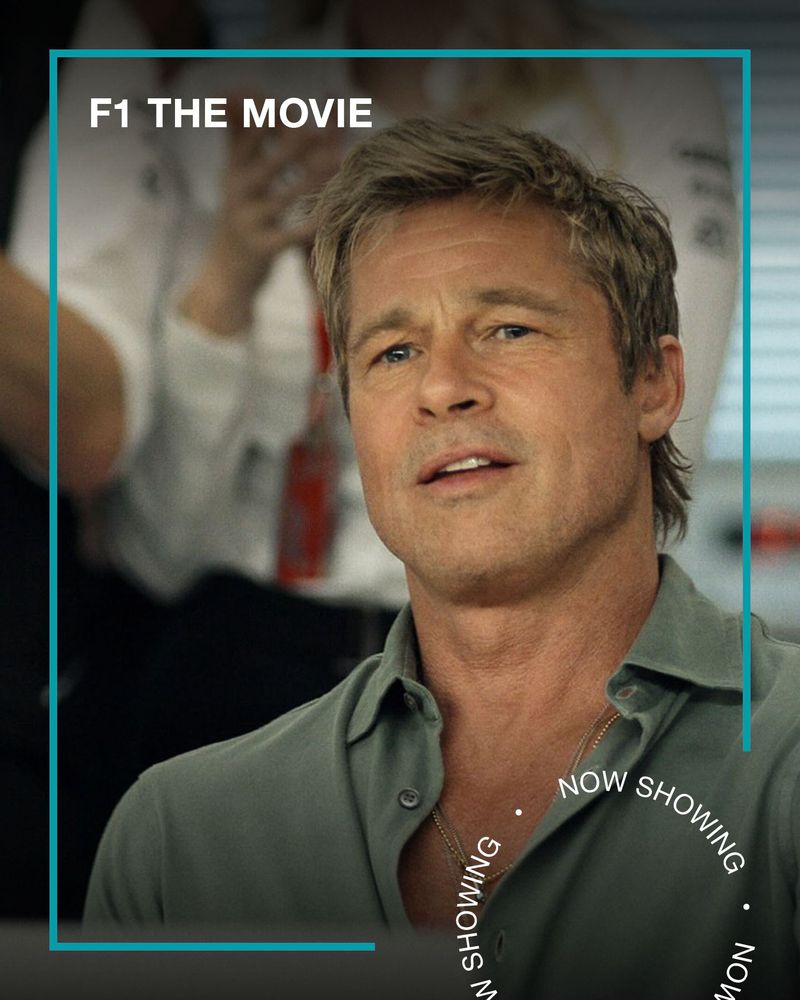 Brad Pitt smiles while sitting at a desk. Text - F1 The Movie, Now Showing.