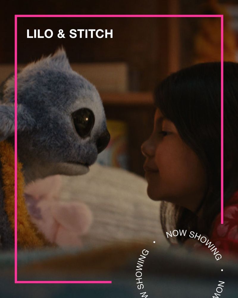 A little girl looks at a blue, fluffy alien. Text - Lilo & Stitch, Now Showing.