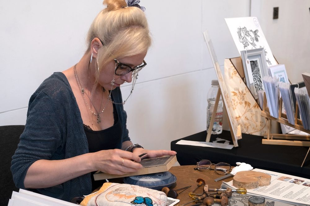 Artist Beth S Robertson engraving a design onto wood