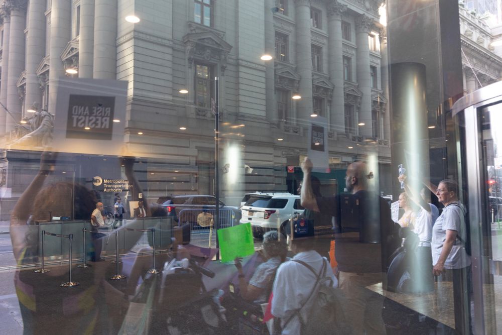 Photo through a window of an MTA employee watching the protesters outside